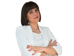 Žena u belom sakou, prekrštenih ruku na grudima, sa osmehom na licu